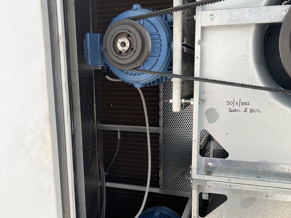 Belt drive and motor inside an air handling unit, with the service date written on the panel