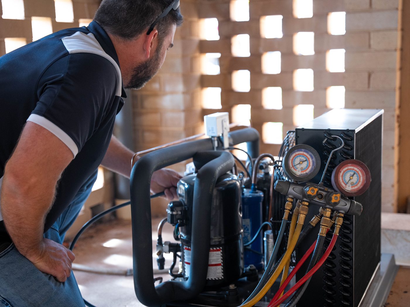 Pristine Cooling technician checking pressures on commercial refrigeration plant with a gauge manifold